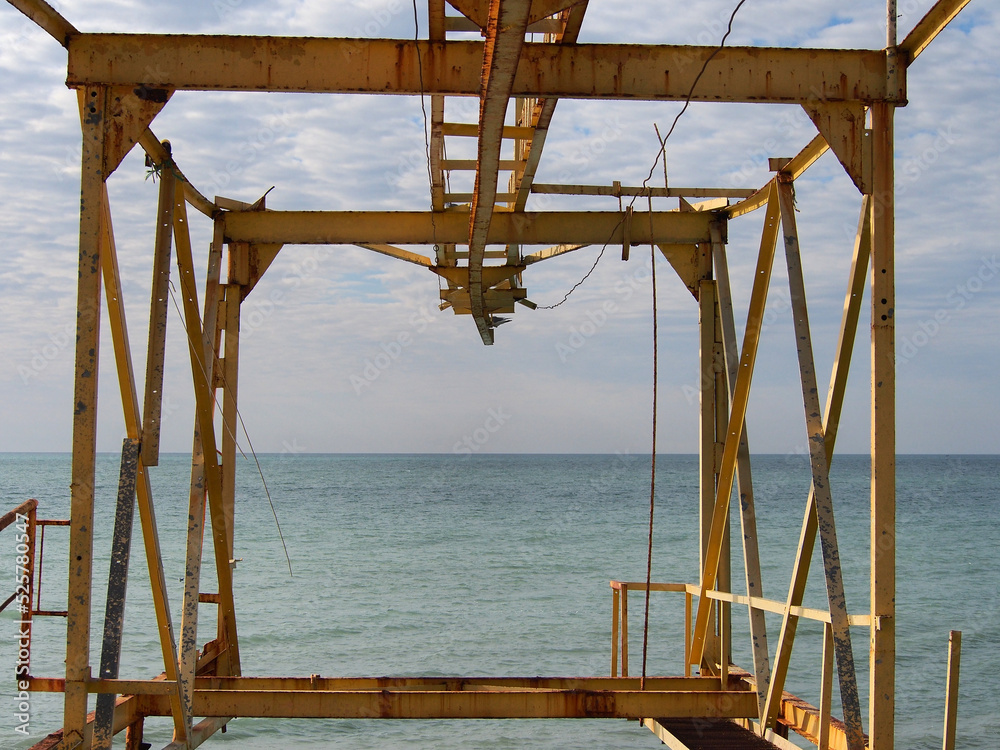 Techno landscape, fragments of metal structures. Metal structures of the lifting mechanism for boats against the background of the sea and cloudy sky. Techno landscape, fragments of metal structures. Metal structures of the lifting mechanism for boats against the background of the sea and cloudy sky.