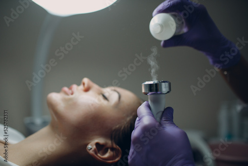 Close up of head woman receiving electroporation phonophoresis facial therapy at beauty spa salon photo