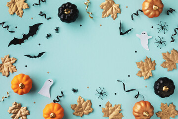 Halloween holiday frame with party decorations of pumpkins, bats, ghosts, spiders on blue background top view. Happy halloween card in flat lay style.