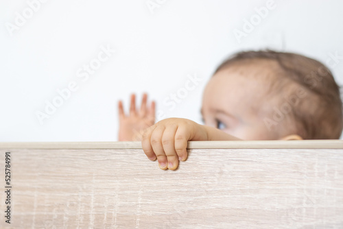 toddler boy in baby crib refuse to stay,get up holding edges with little hands or push bars with feet.train to sleep in own bed,maternity,upset angry infant.home interior,sun rays falling in room