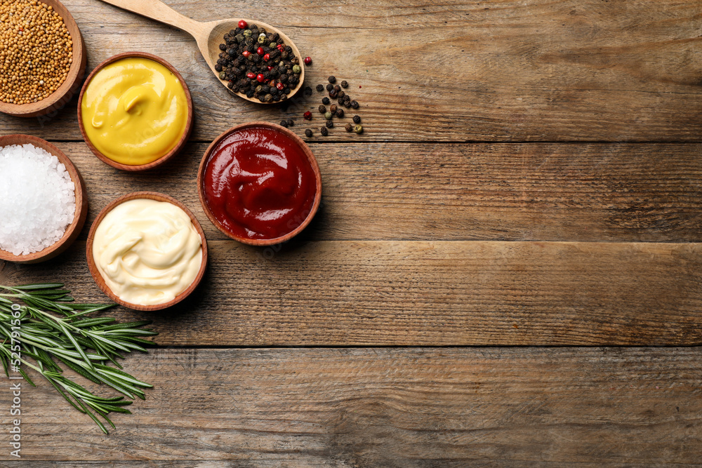 Flat lay composition with ketchup, mustard, mayonnaise and ingredients on wooden table, space for text Flat lay composition with ketchup, mustard, mayonnaise and ingredients on wooden table, space for text