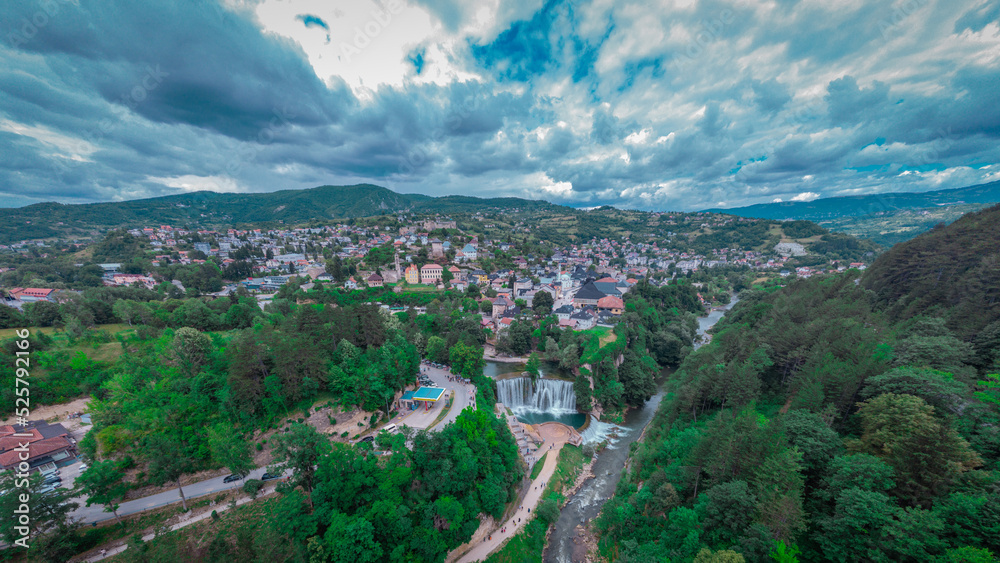 Pliva river waterfall and panorama of Jajce city in western Bosnia. Drone perspective or aerial photo of Jajce in a cloudy day.