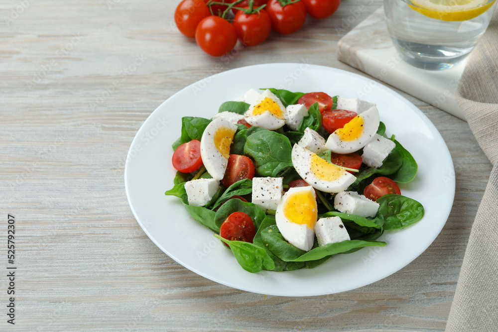 Delicious salad with boiled eggs, feta cheese and tomatoes on wooden table Delicious salad with boiled eggs, feta cheese and tomatoes on wooden table