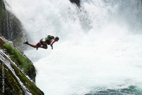 waterfall extreme brave man as superhero running jump and dive from the rock into the wild river water.