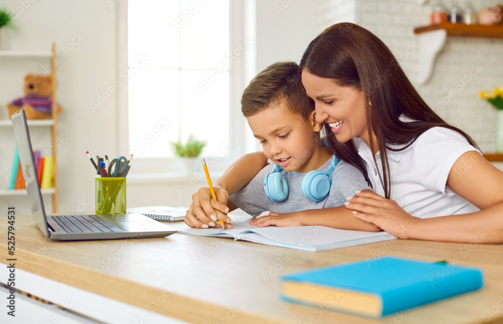 Woman spending time at home for studying with lovely son. Friendly caring young mother is teaching her preschooler son to write letters at home. Family sits at table and writes with pencil in notebook Woman spending time at home for studying with lovely son. Friendly caring young mother is teaching her preschooler son to write letters at home. Family sits at table and writes with pencil in notebook