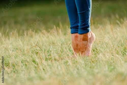 Closeup of woman with bare feet stretching muscles in summer park
