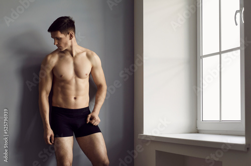 Handsome Young Toned Muscular Man In Underwear Pose On Grey Wall Background  Advertise Briefs. Sexy Sporty Guy Model In Underclothing Garment Recommend  Good Fashion Or Style. Ad Concept. Stock Photo, Picture and