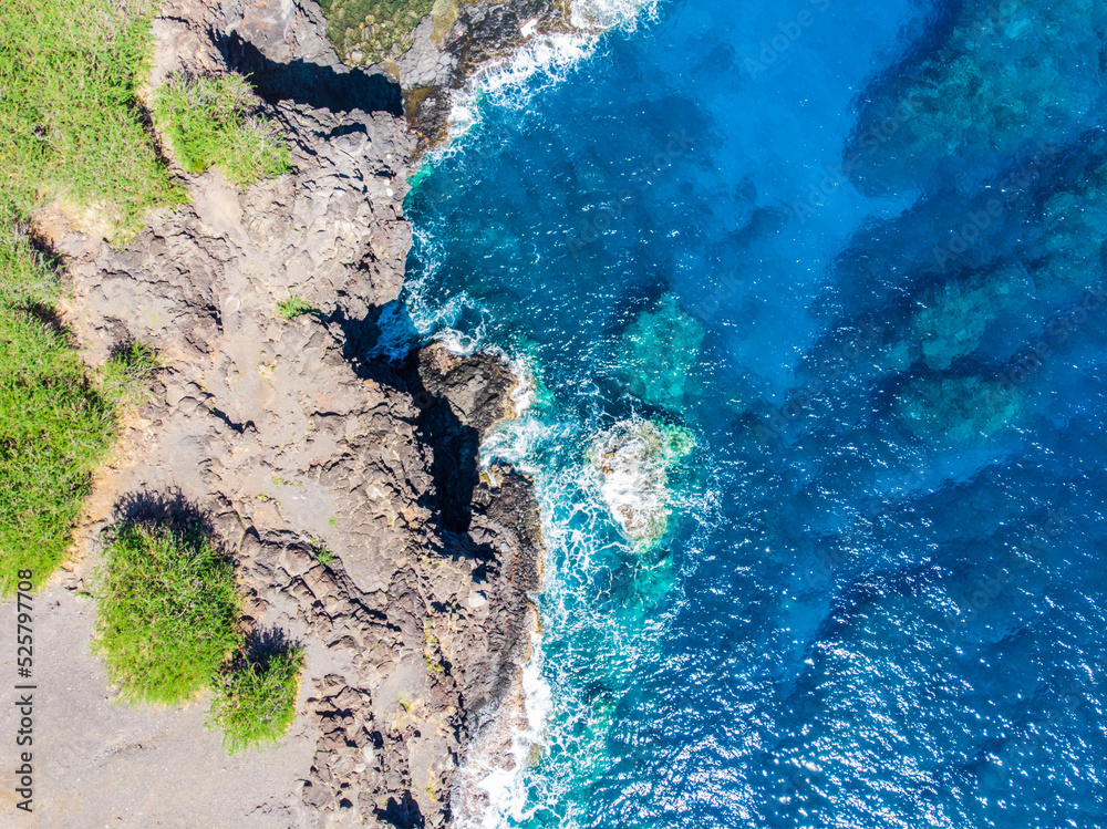 Vue aérienne verticale d'un littoral tropical dans l'océaen Indien avec écume sur l'eau à flanc de falaise, La Réunion