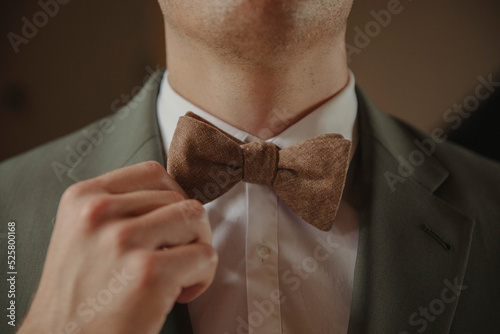 groom adjusting brown bow