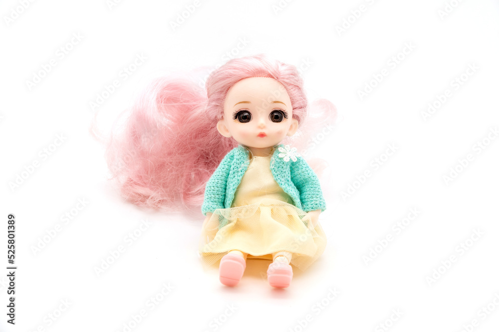 little plastic doll, baby girl. Little blonde doll with blue eyes on white bg. Isolated on white background with shadow reflection. With red shirt and checkered pants.