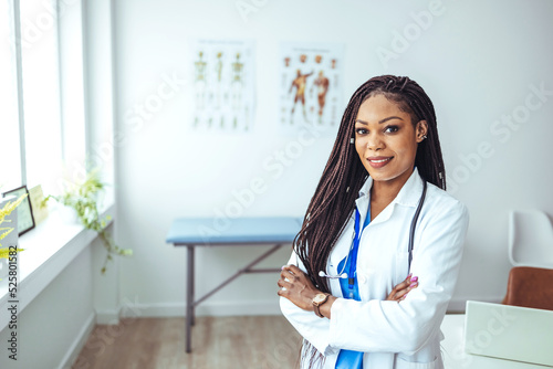 Portrait of happy young female doctor standing in hospital corridor. Caucasian woman working in healthcare center. Portrait of a mature female doctor standing in a hospital corridor