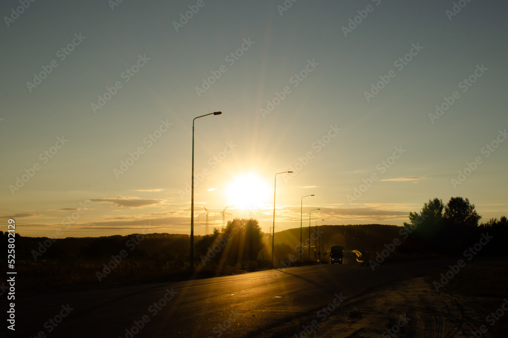 Asphalt road outside the city against the background of the sky with a bright sunset