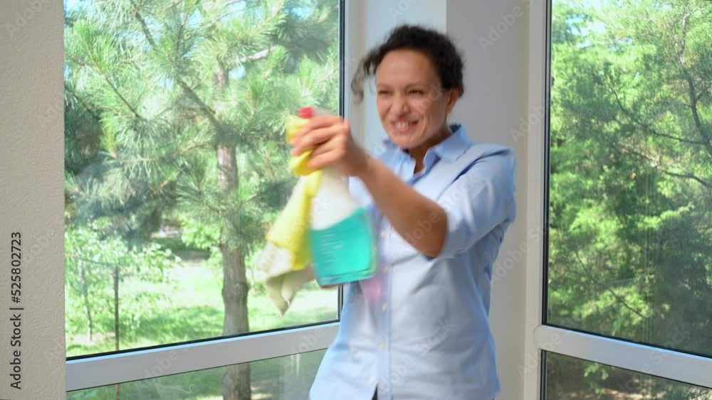 Beautiful funny Latin American woman, lovely housewife sprinkling the sprays detergent around, dancing and happily doing household chores in the home veranda. Housekeeping. Cleaning service. Housework Beautiful funny Latin American woman, lovely housewife sprinkling the sprays detergent around, dancing and happily doing household chores in the home veranda. Housekeeping. Cleaning service. Housework