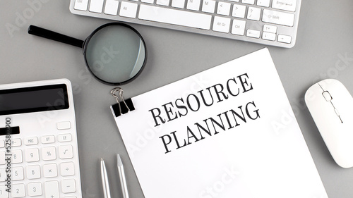 RESOURCE PLANNING written on paper with office tools and keyboard on the grey background