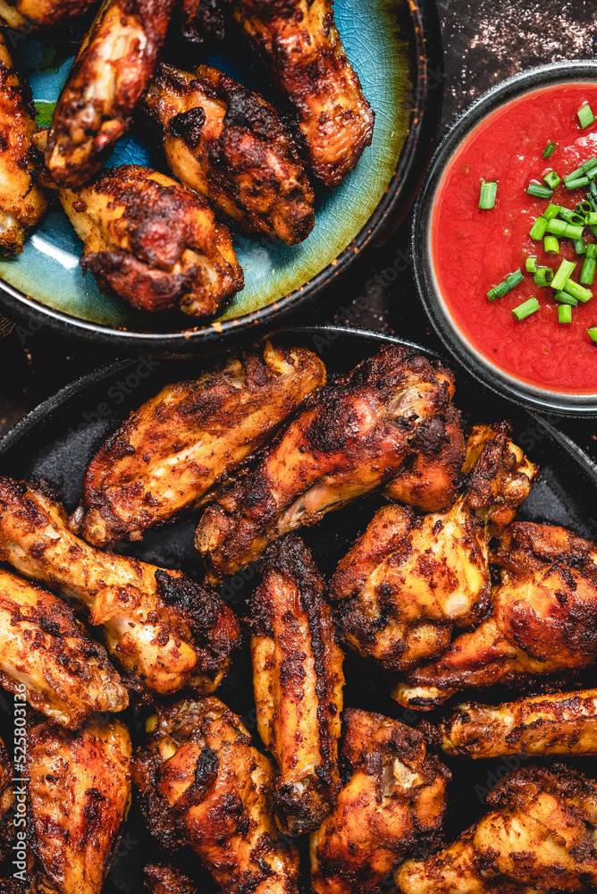 Grilled chicken wings on a black plate on a dark rustic background