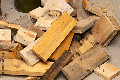 Wooden scraps from the boards are lying in a heap on the floor. Waste of woodworking production.