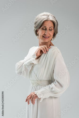 smiling middle aged bride in white wedding dress isolated on grey