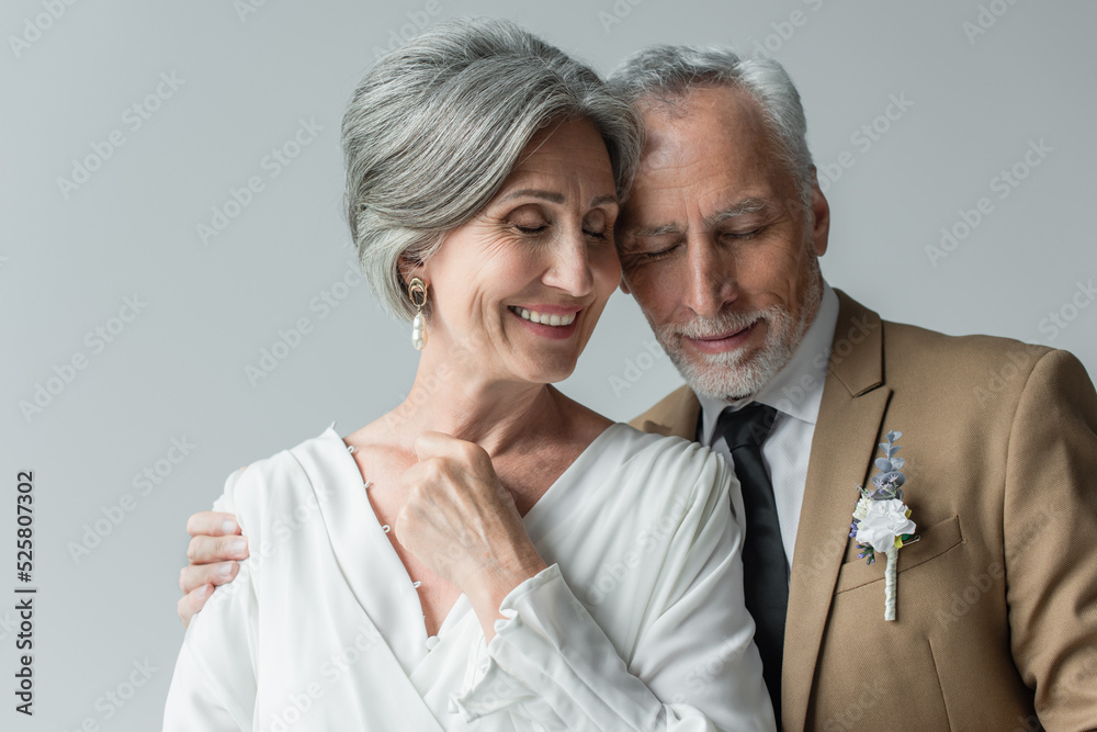 cheerful middle aged man in suit with floral boutonniere and woman in white wedding dress isolated on grey cheerful middle aged man in suit with floral boutonniere and woman in white wedding dress isolated on grey