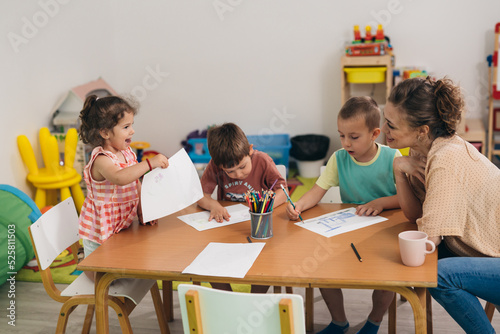 children drawing with teacher assistance in day care