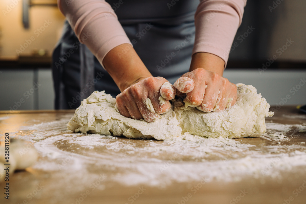 close up of woman hands kneading the dough in home kitchen