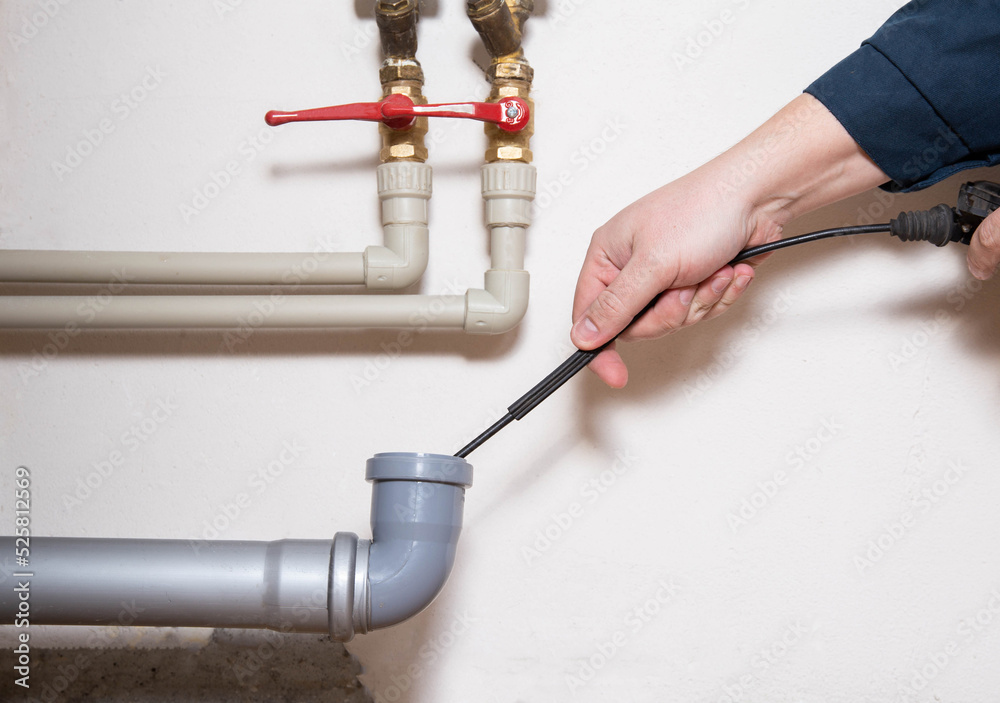 Cleaning the sewer drain pipe with a manual plumbing cable. Sewer blockage, close-up