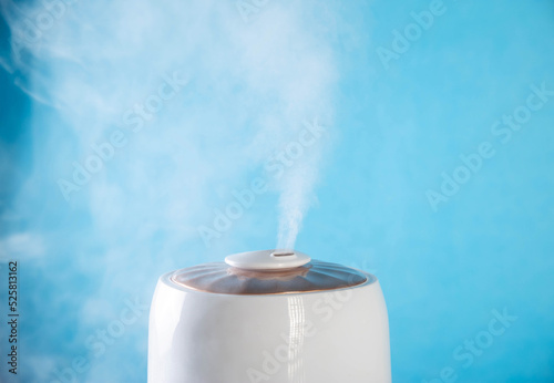 White wet steam from a humidifier on a blue background. Device for healthy air in the room, close-up