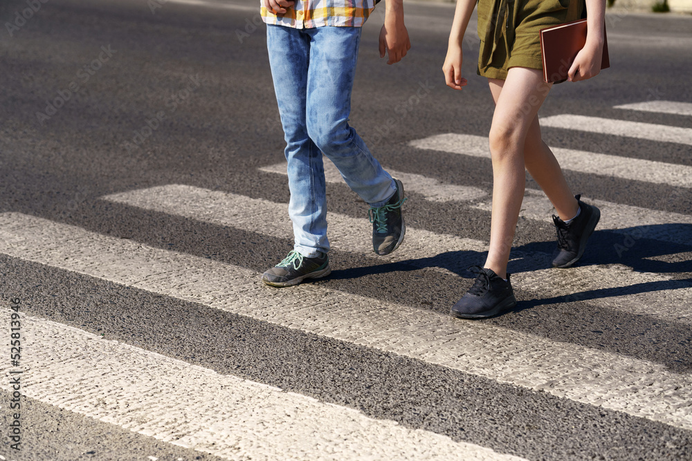 teenage schoolchildren, a boy and a girl cross the road at a pedestrian crossing teenage schoolchildren, a boy and a girl cross the road at a pedestrian crossing