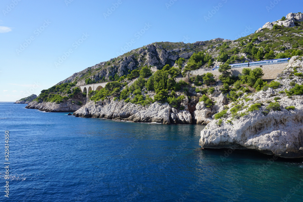view of the mediterranean rocky coast and the blue sea in the calanques france with the train going by across the  stone bridge
