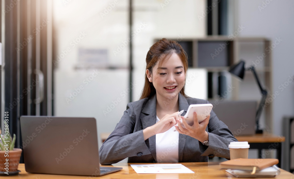 Young Asian businesswoman using a calculator to calculate business principles. Accounting statistics concept at the office. Young Asian businesswoman using a calculator to calculate business principles. Accounting statistics concept at the office.