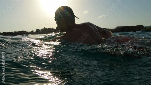 Ocean swimming slow motion shot. Athletic Young man professional triathlon swimmer practicing at morning sea. 