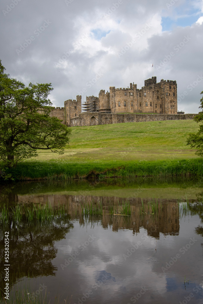 Alnwick Castle reflected in the water of the River Aln. Northumberland, UK