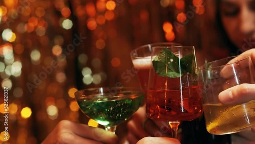 Friends in an expensive and shiny restaurant clink glasses of cocktails, rejoice, laugh and drink.