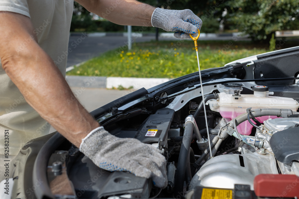 a man checks the oil level in a car engine a man checks the oil level in a car engine