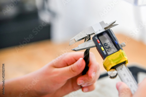 Wallpaper Mural The girl measures the diameter of the drill with an electronic caliper. Torontodigital.ca