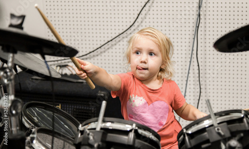 A little girl tries to play the drum kit at a music school.