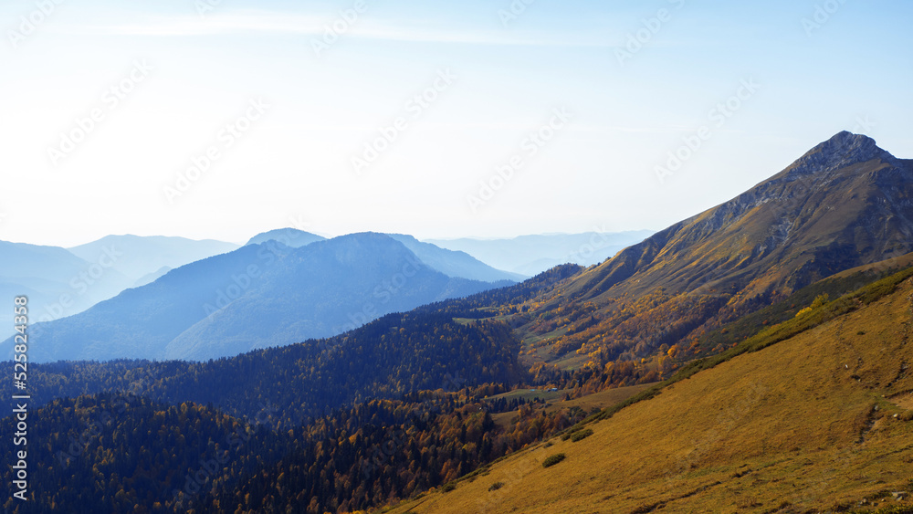 A beautiful panorama of mountains, aerial perspective, distant peaks in a blue haze, freedom and beauty of nature. Autumn view of the Caucasus mountains in Russia