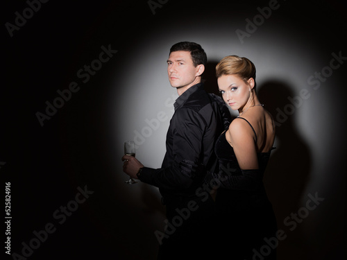 An attractive couple in black. Stylish and elegant young man and woman in the spotlight. Beautiful blonde in a long dress