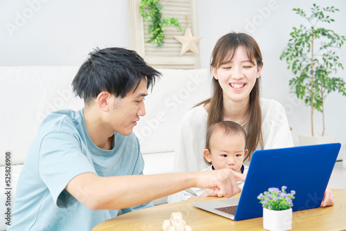 リビングでノートパソコンを見る両親と赤ちゃん