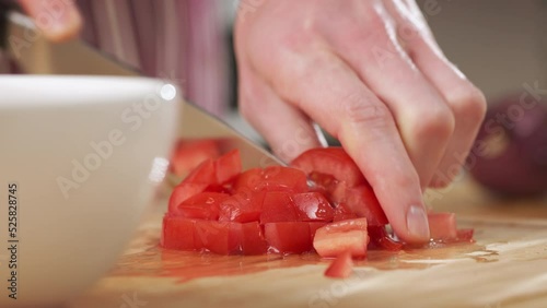 Home chef making salsa in the kitchen - chopping tomatoes. Closeup handheld shot.