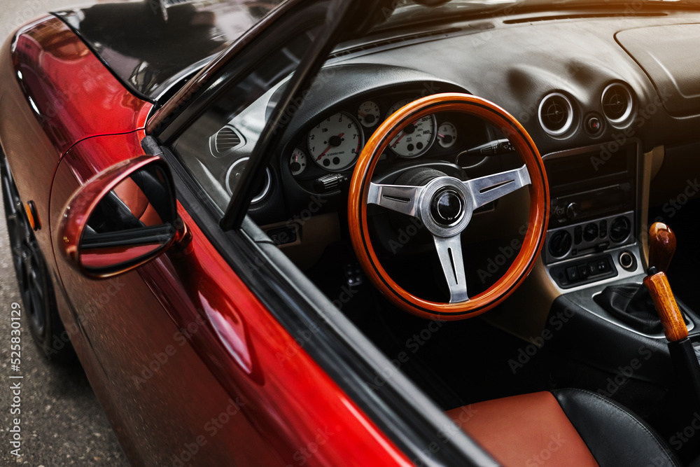 leather interior and sports steering wheel of a red convertible. car exterior