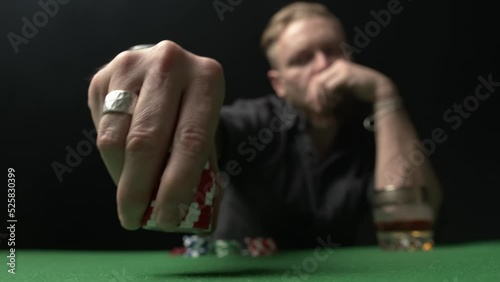 A poker player makes a bet. Takes a stack of red chips and confidently puts them on the table close-up