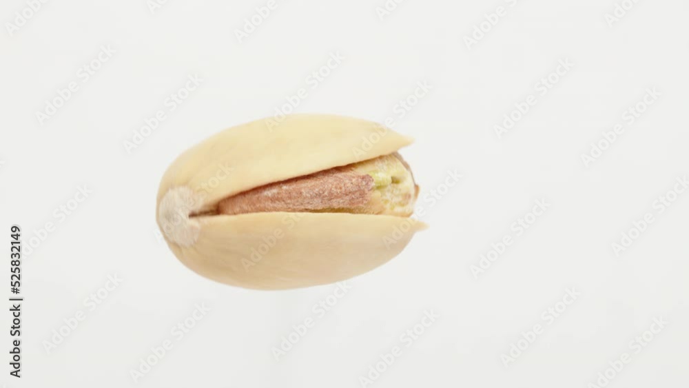 One salted pistachio is spinning on a white background. Close-up. One salted pistachio is spinning on a white background. Close-up.