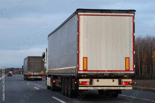 White heavy trucks convoy on countryside highway road.