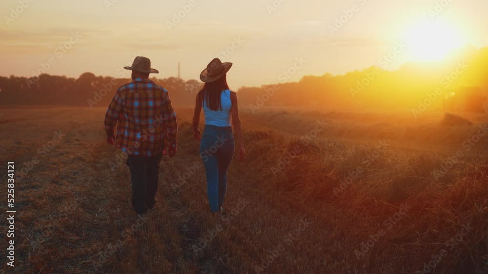 Back view of two farmers: man and woman walking along plowed field on ...