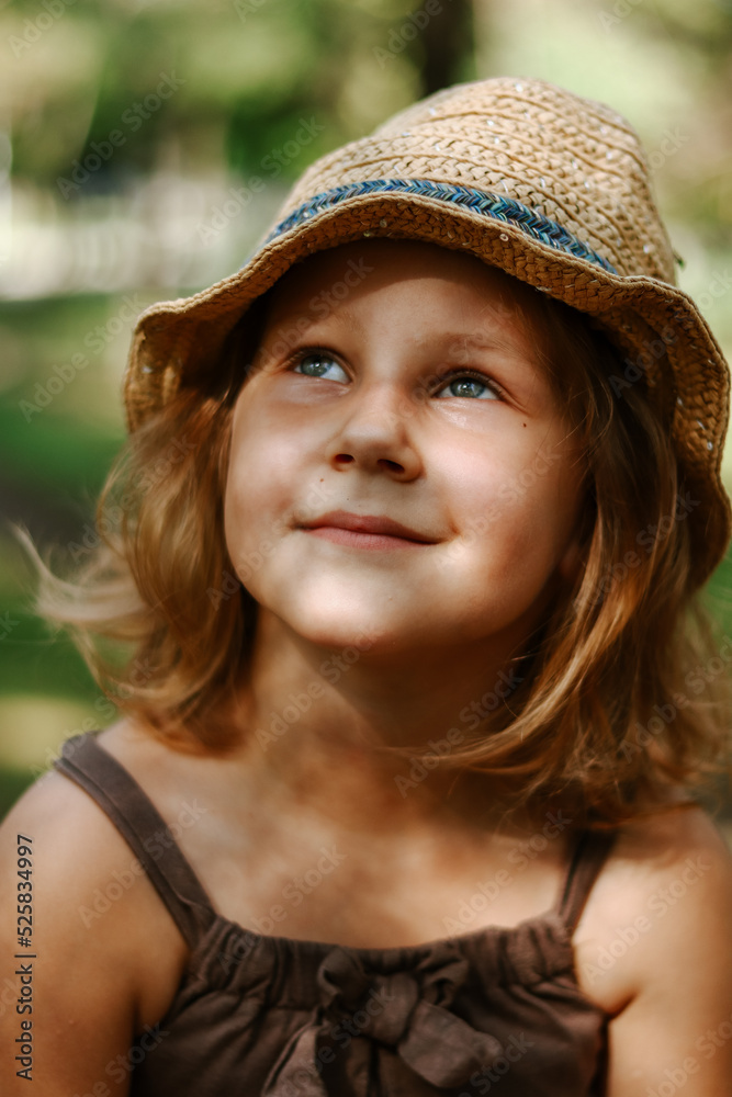 Cute blonde child 5 years old. Child in a straw hat. Portrait of a baby girl close-up. To look up.
