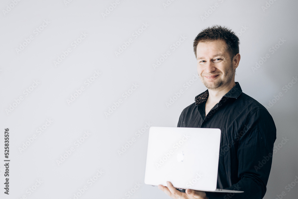Confident IT specialist in black shirt holding laptop and smiling. Confident IT specialist in black shirt holding laptop and smiling.