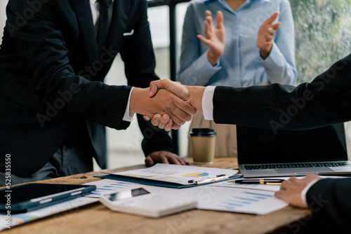 Close up of female and male shaking hands, businessman and businesswoman handshaking at office table with charts graphs after successful negotiations, partners concluding contract