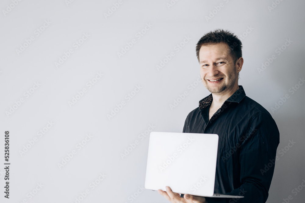 Confident IT specialist in black shirt holding laptop and smiling. Confident IT specialist in black shirt holding laptop and smiling.