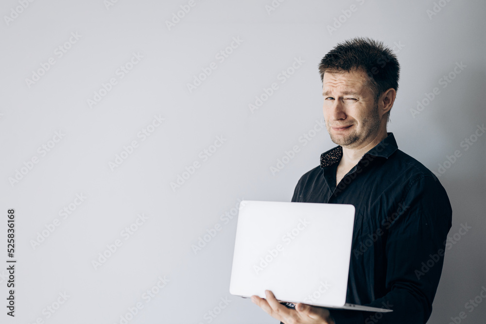 Confident IT specialist in black shirt holding laptop making faces. Confident IT specialist in black shirt holding laptop making faces.