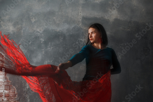 Young adult spanish woman dancing flamenco on gray vintage studio background with shawl